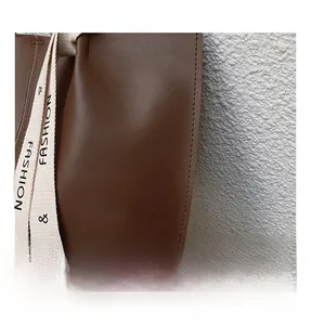 Detail of brown pebbled leather tote bag with white 'FASHION' lettered textile strap