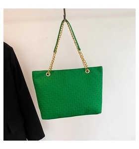 Primer plano de bolso tote tejido verde con textura y correa de cadena dorada