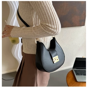 Detail of minimalist black crescent bag featuring a vintage gold rectangular twist lock