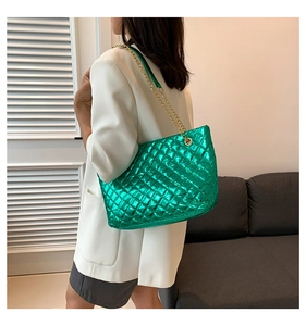 Détail du sac cabas matelassé vert émeraude métallisé avec chaînes dorées sur costume blanc