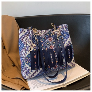 Close-up of ethnic tote bag with HOOO patch, metal chain handle, and woven patterns