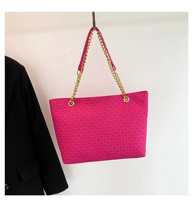 Detalle del bolso tote tejido magenta con cadena dorada y almohadilla para el hombro