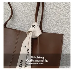 Close-up of matte dark brown leather tote with precise stitching and fashion webbing detail