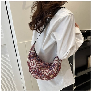 Detailed side view of vintage geometric woven crescent bag on model in casual white shirt