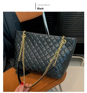 Detailed view of black quilted tote bag with golden chain strap on a brown chair