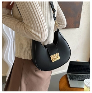 Close-up of black crescent hobo bag featuring a gold rectangular twist lock and fine texture