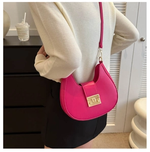 Detail of fuchsia leather crescent bag showing the gold buckle and shoulder strap texture
