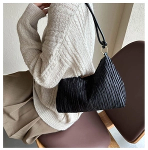 Détail du sac à bandoulière plissé noir avec anneaux métalliques dorés et fine bandoulière