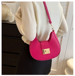 Detailed view of fuchsia saddle bag with adjustable strap and golden buckle clasp