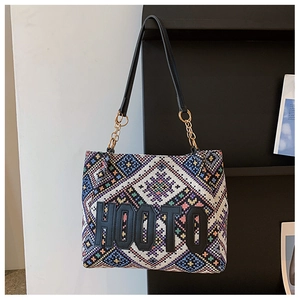Close-up of geometric ethnic fabric pattern with HOOTO logo patch and gold chain strap