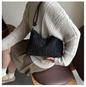 Détail du sac à bandoulière plissé noir avec des nœuds élégants sur la lanière
