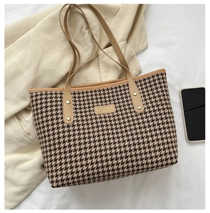 Detail of houndstooth tote bag featuring premium brown leather straps and gold rivets
