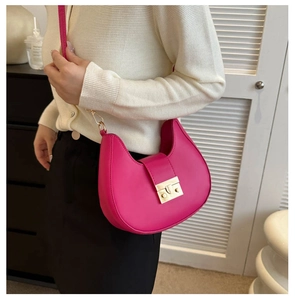 Side view of vibrant hot pink crescent shoulder bag with golden metallic push buckle