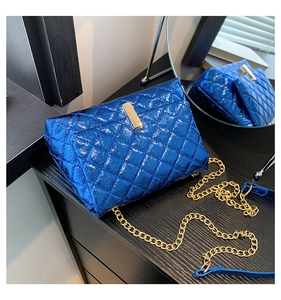 Close-up of quilted blue metallic patent leather bag with gold chain strap and lock