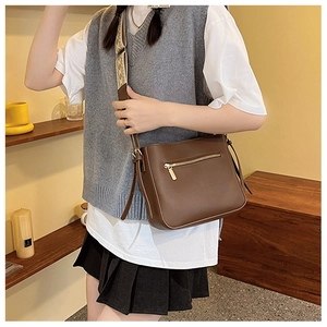 Detail of dark brown crossbody bag with jacquard strap and gold zipper pocket
