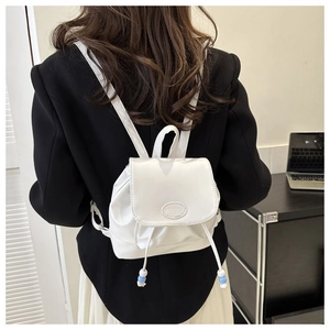 Nahaufnahme eines weißen Mini-Rucksacks mit Deko-Perlen und geprägtem Fashion-Logo