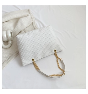 Vista superior de un bolso tote blanco de cuero con cadena sobre fondo minimalista