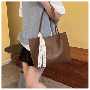Detail of a large brown tote bag with fashion ribbon and smooth faux leather texture