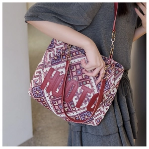 Detail of ethnic woven tote bag with red leather letters and golden chain strap detail