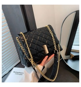 Close-up of black quilted chain bag featuring glossy patent leather and gold hardware detail