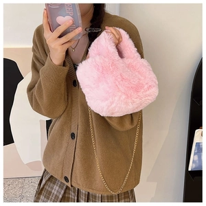 Sac seau rose en peluche avec chaîne dorée porté à l'épaule par un mannequin