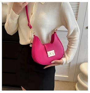 Detail of fuchsia saddle bag with gold buckle and adjustable leather strap on model