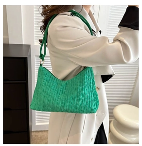 Détail de la texture plissée vert vif et de la bandoulière d'un sac cabas élégant
