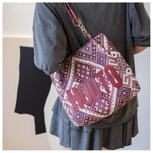 Detail of ethnic geometric woven pattern and leather strap on a large tote bag