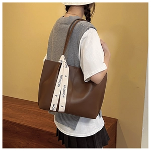 Close-up of a dark brown large tote bag with a decorative ribbon on the handle