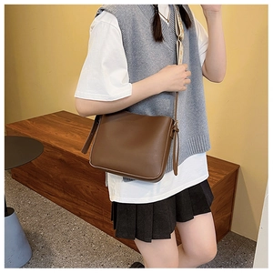 Close-up of a minimalist dark brown leather crossbody bag with neat stitching detail