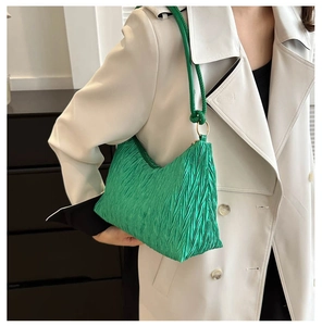 Détail du sac bandoulière plissé vert vif avec anneaux dorés et bandoulière fine