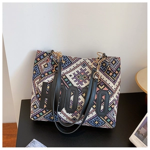 Close-up of geometric ethnic woven pattern with leather letter patches on large tote bag
