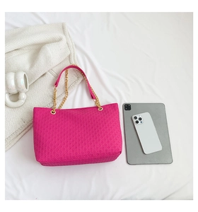 Detalle de bolso tote fucsia con textura geométrica, cadena y tableta para escala de tamaño