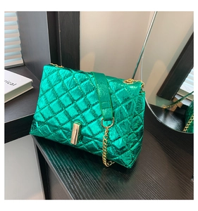 Detail of bright green quilted shoulder bag with metallic finish and gold chain strap