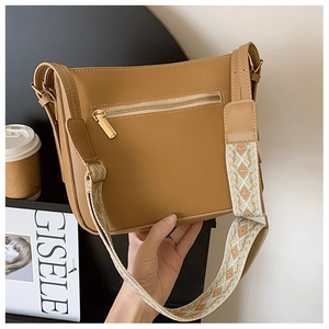 Close-up of vintage brown leather crossbody bag with geometric pattern wide shoulder strap