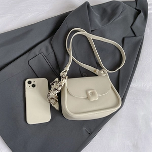 Minimalist cream shoulder bag with floral scarf detail on dark blazer background
