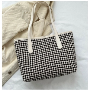Detailed view of houndstooth tote bag fabric texture with cream leather handle trim