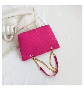 Detalle de bolso bandolera rojo rosa con textura geométrica y correa de cadena dorada