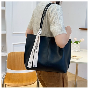 Close-up of black PU leather tote bag with decorative fashion scarf on shoulder strap