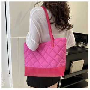 Dettaglio di una grande borsa tote trapuntata rosa acceso indossata da una modella