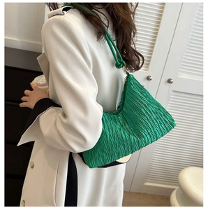Vue latérale du sac demi-lune plissé vert vif porté sur un trench-coat blanc chic