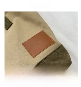 Dettaglio delle cuciture a contrasto e della toppa in pelle marrone su borsa in tela beige