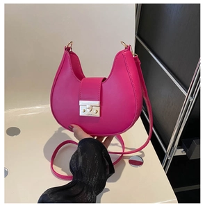 Detail of bright pink crescent bag with golden rectangular metal clasp and thin strap