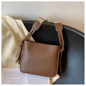 Detail of a brown PU leather bucket bag with bohemian printed wide shoulder strap