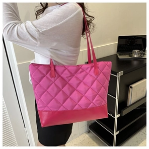 Dettaglio della borsa tote trapuntata rosa con trama in nylon e base in pelle sulla modella