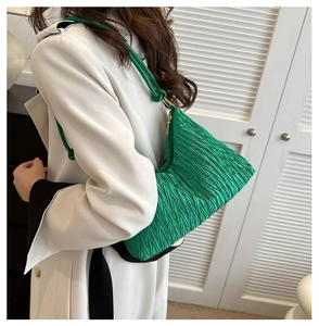 Détail du sac cabas plissé vert porté par un mannequin sur fond blanc minimaliste
