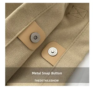 Dettaglio ravvicinato della chiusura magnetica in metallo su una borsa tote in tela color kaki