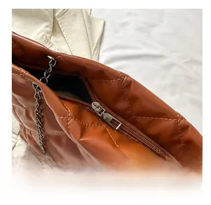 Détail de la fermeture éclair en métal et de la texture matelassée du sac marron