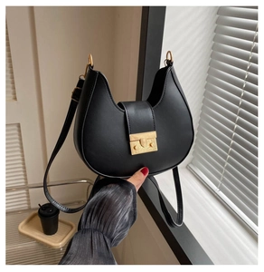 Detail of a matte black crescent shoulder bag featuring a vintage golden square buckle