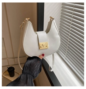 Detail of white hobo bag with sleek PU leather and a golden geometric buckle closure